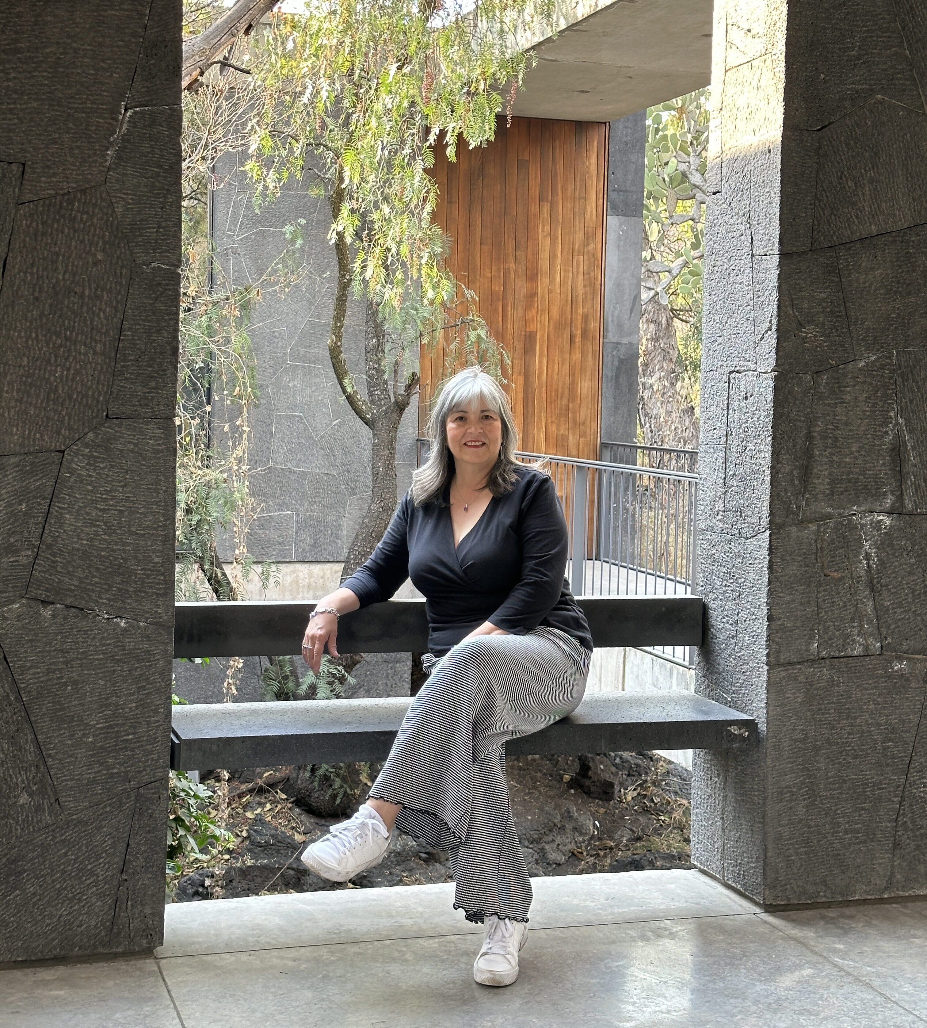 Analee McClellan, Principal, sitting on a stone bench in an outdoor garden