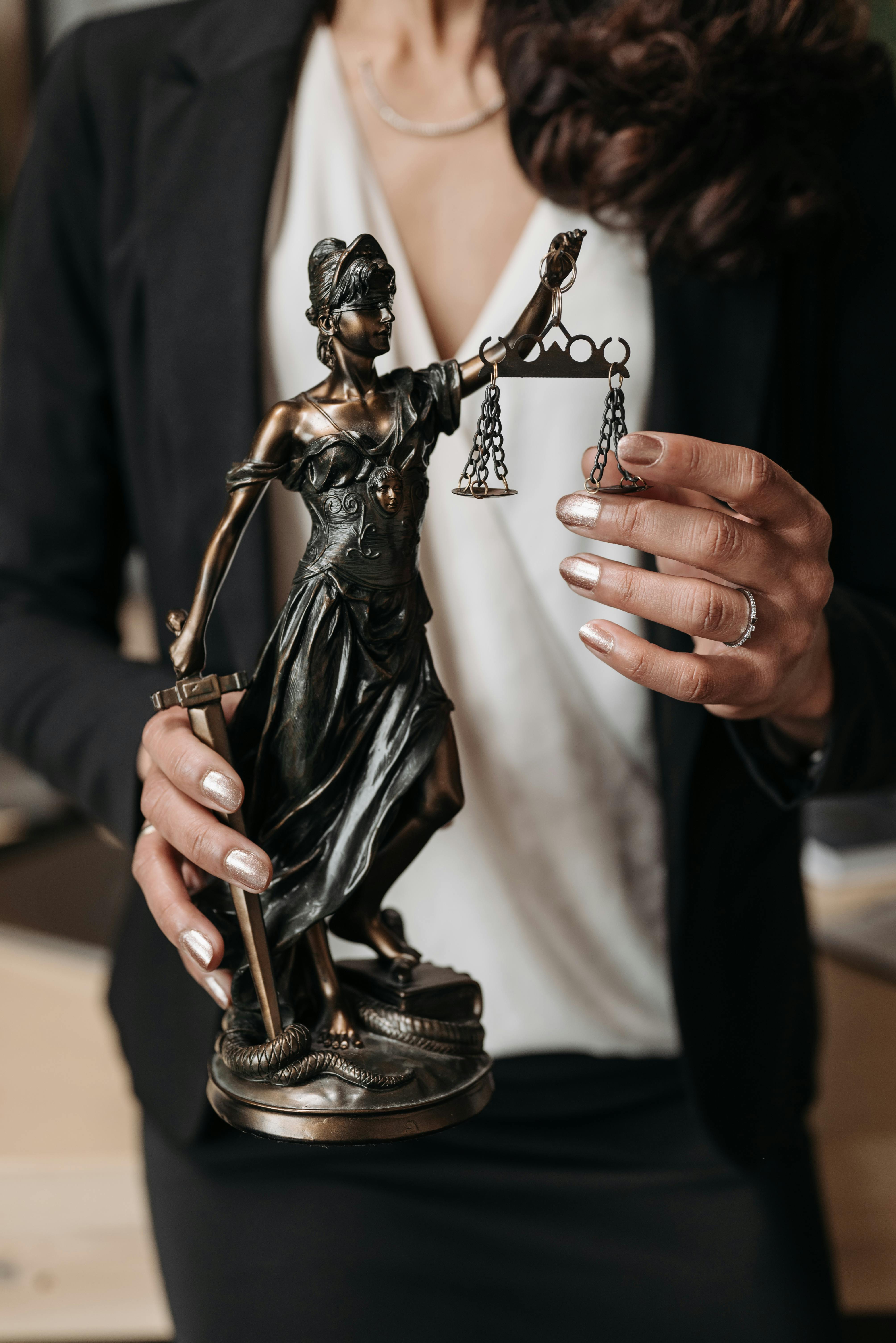 Bronze Blind Justice sculpture being held out and shown by a woman