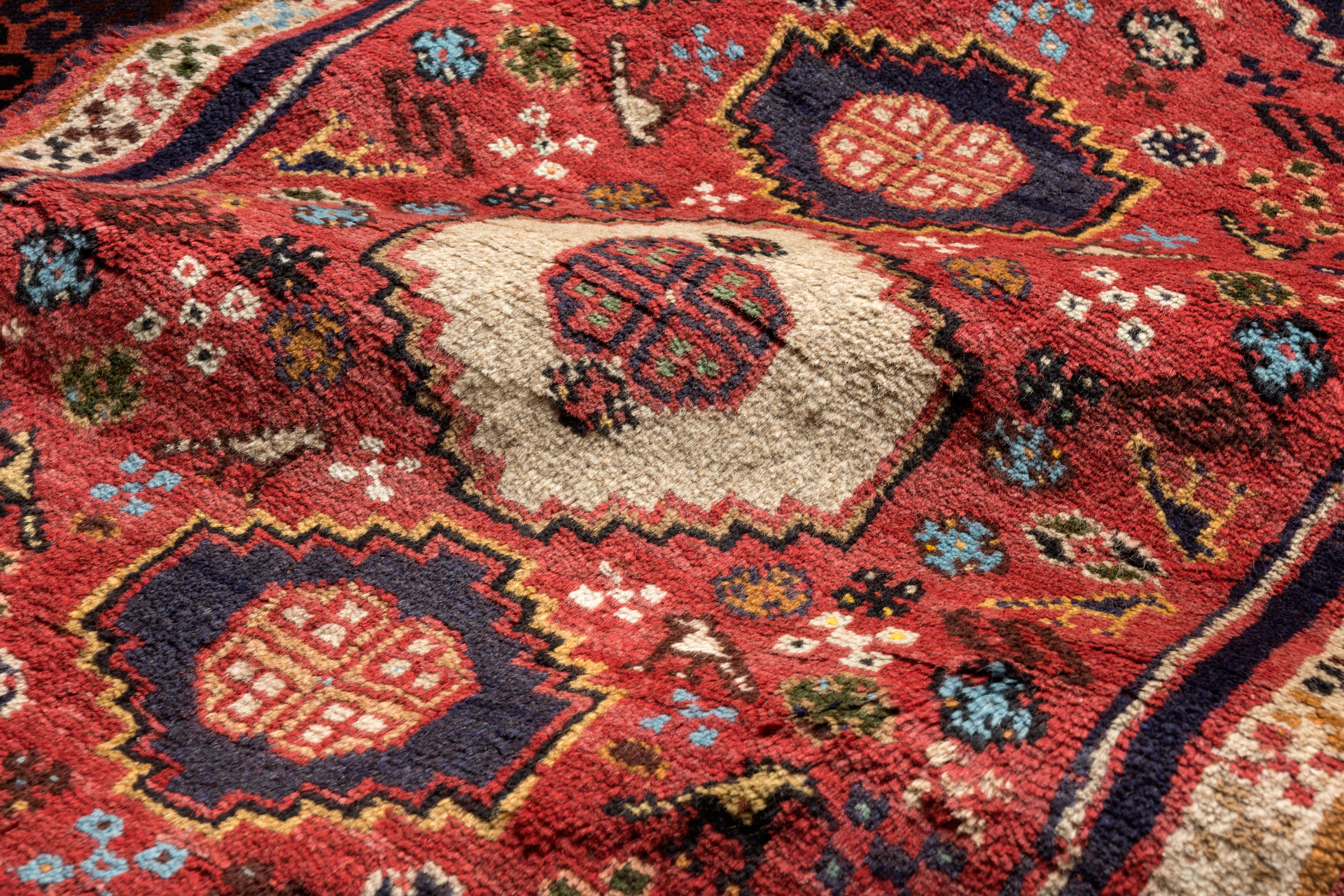 Closeup of a red hand-knotted Persian Shiraz carpet with geometric patterns