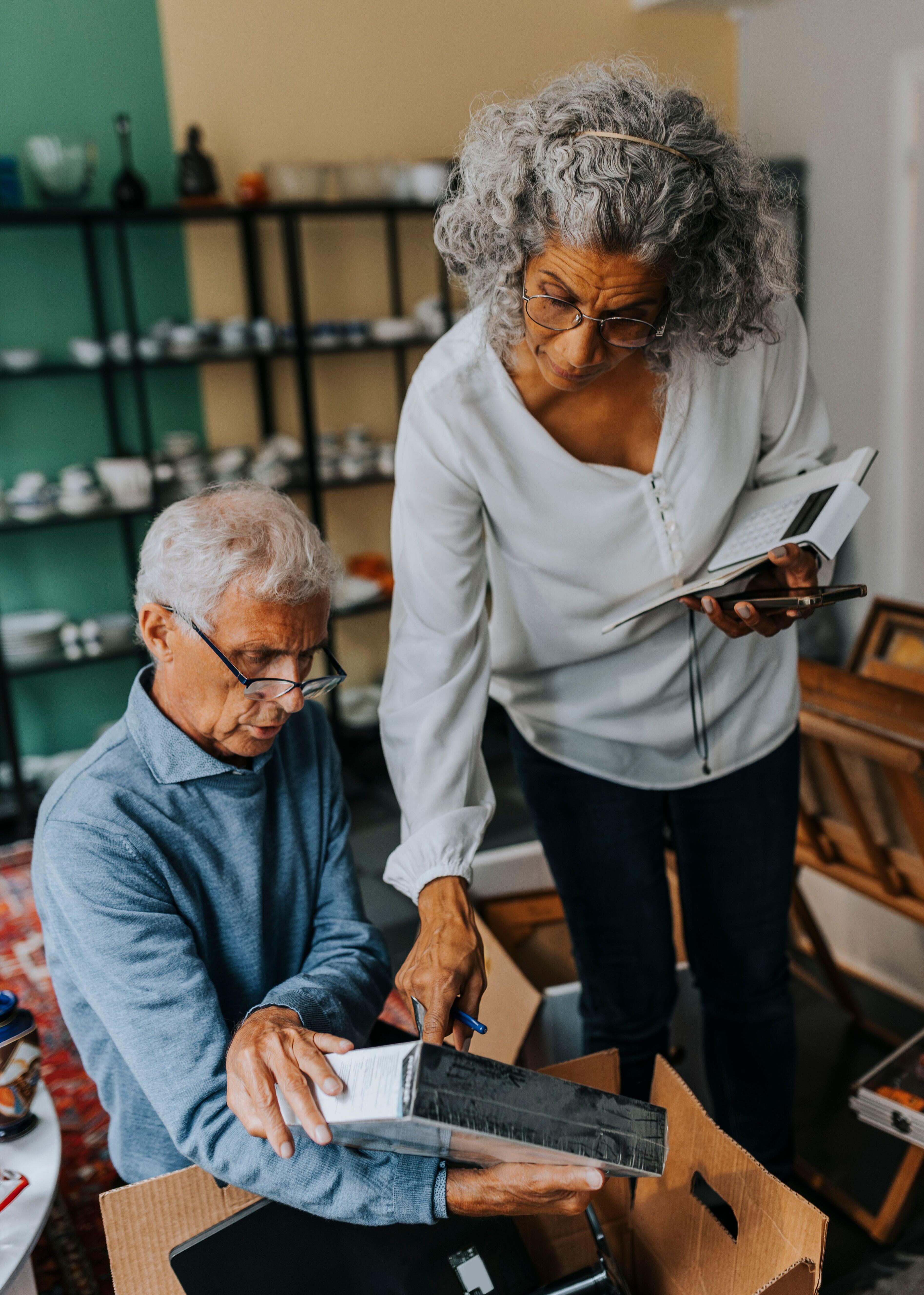 Seated man and standing woman inspecting a package from a cardboard box