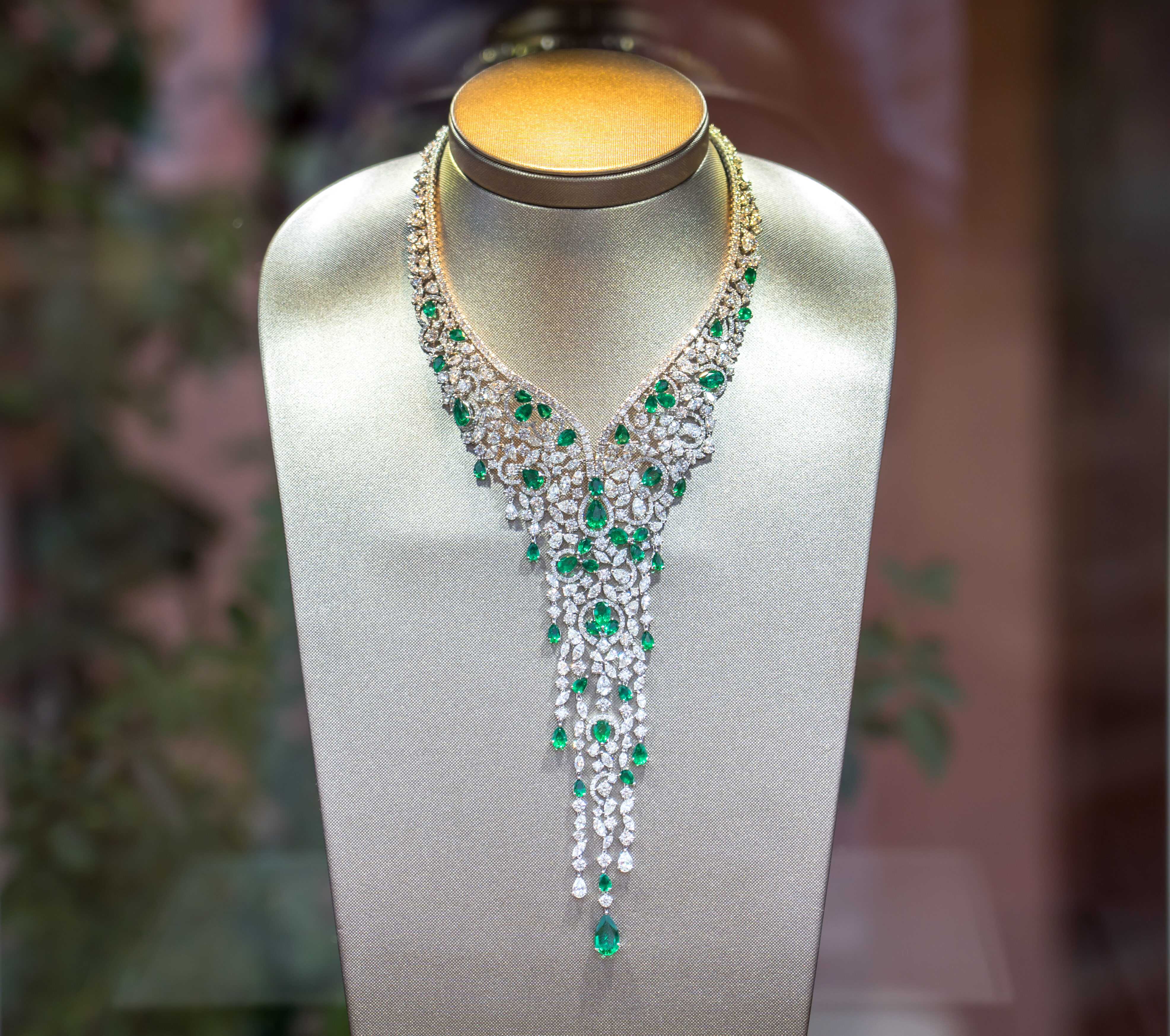 Long diamond and emerald necklace on a display stand