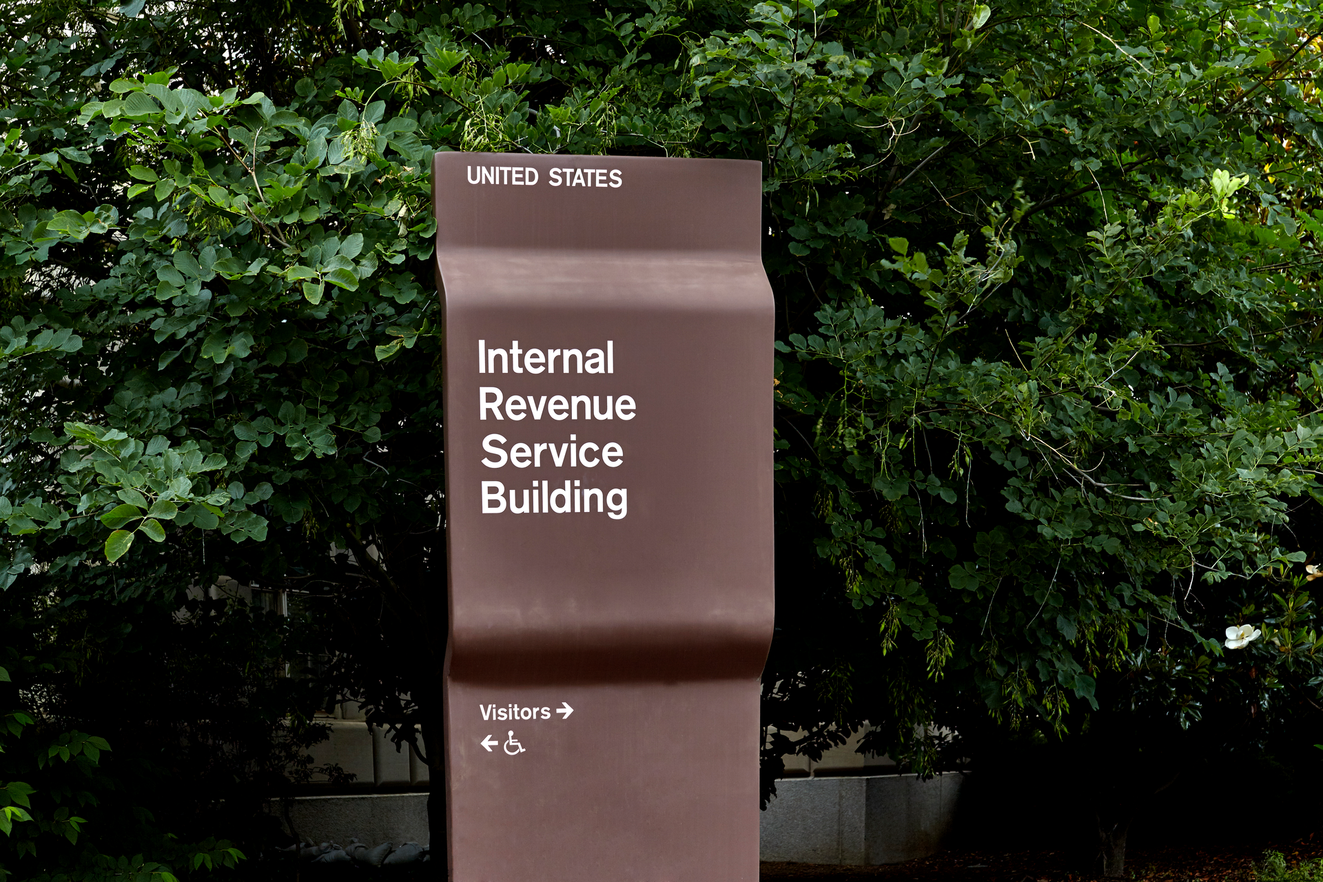 Brown Internal Revenue Service Building sign in front of shrubbery