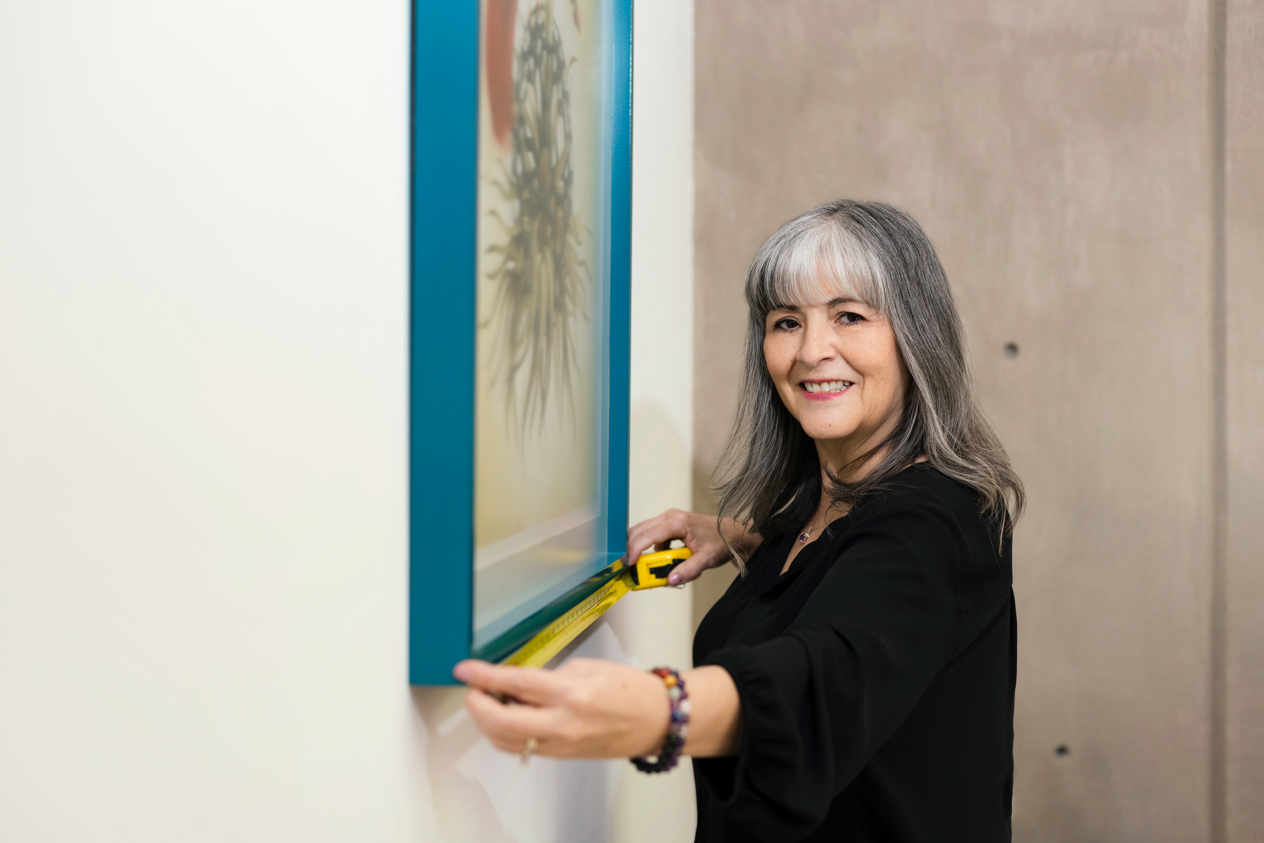 Analee McClellan, Principal, measuring a colorful artwork on the wall