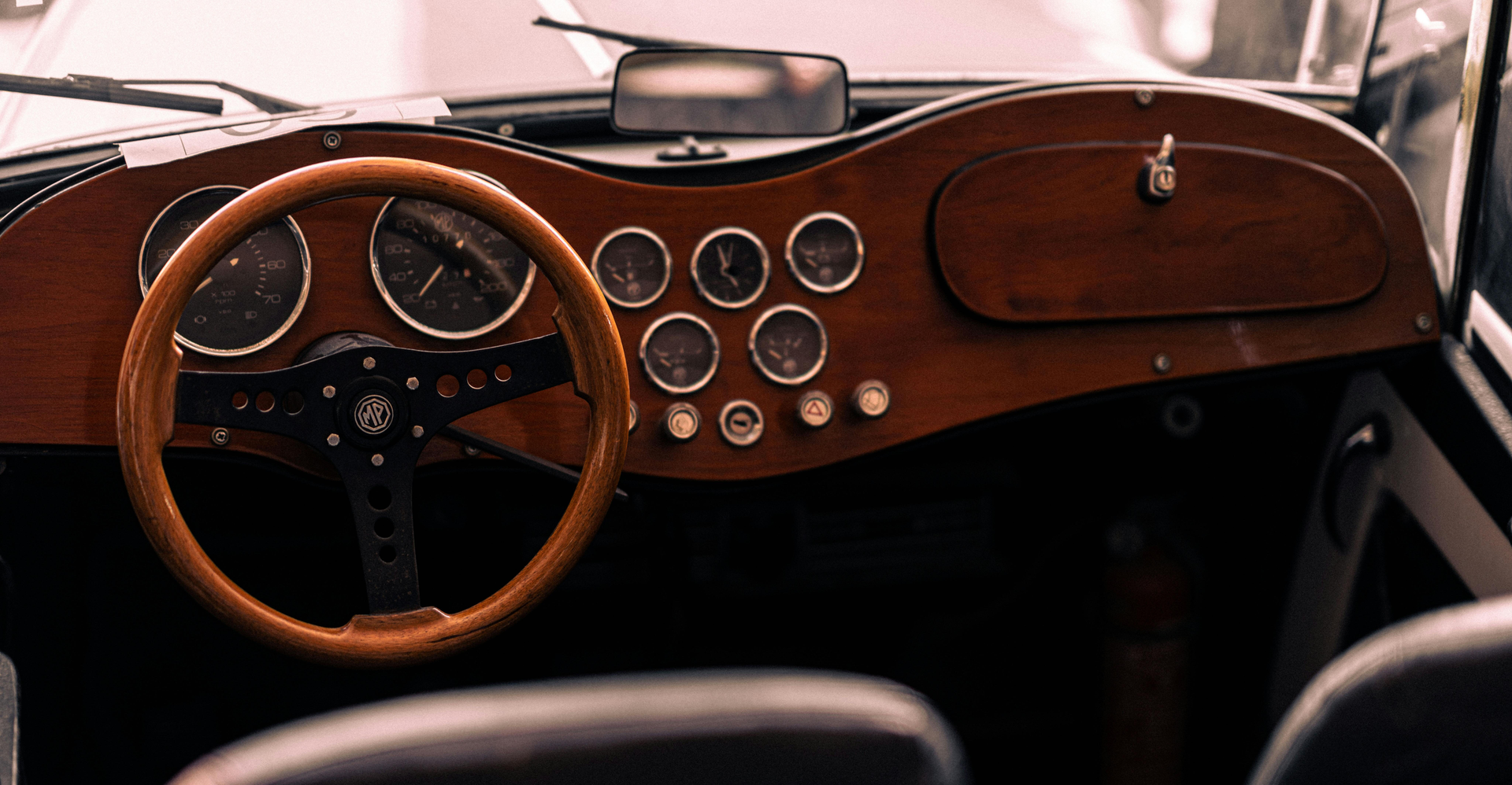 View of a car interior with wooden dashboard and steering wheel and round dials