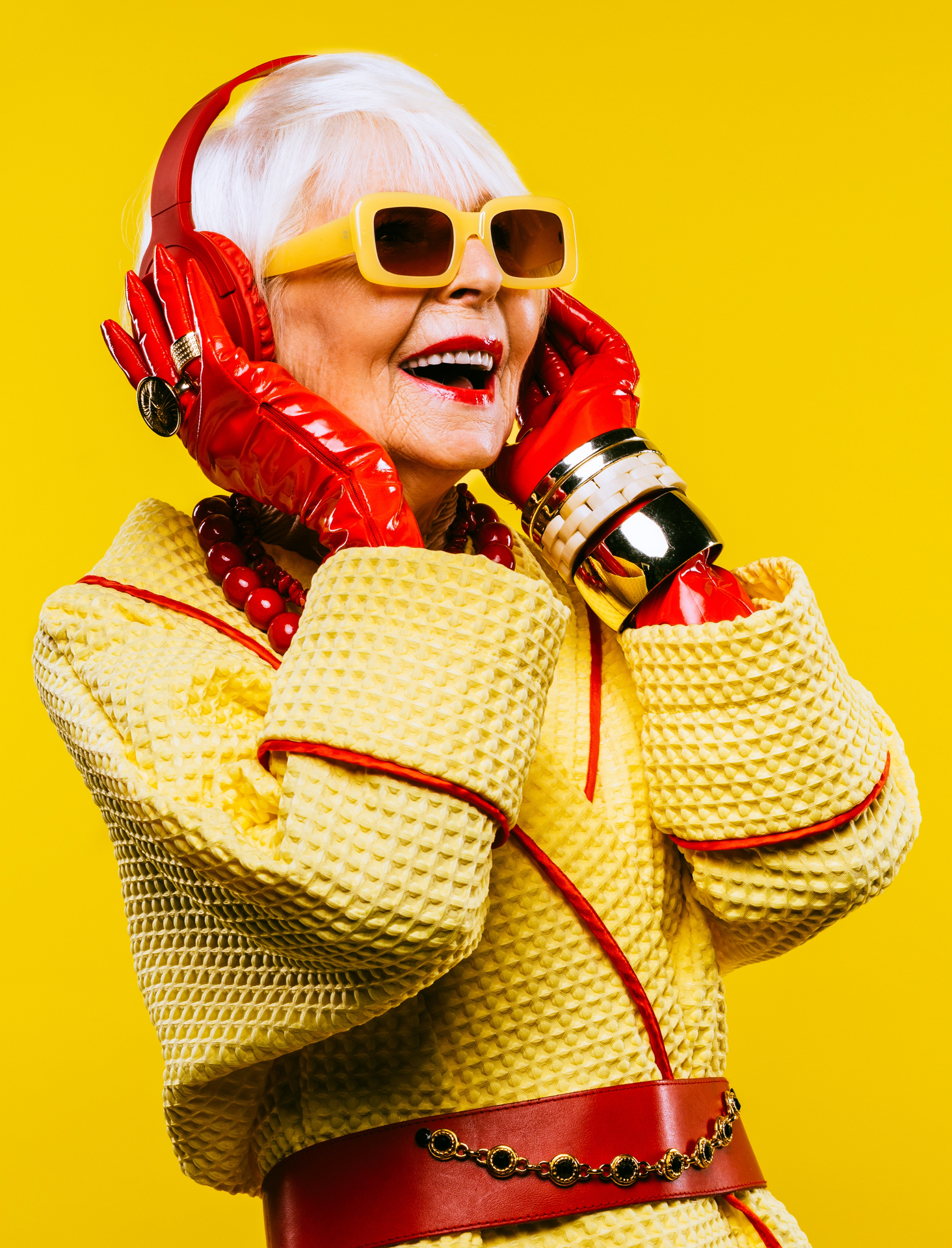 Stylish older woman wearing yellow and bright red clothes and red headphones